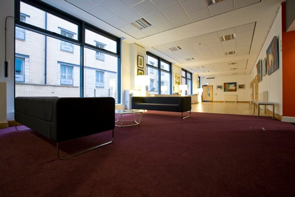 A spacious gallery featuring a large window and a comfortable couch for relaxation or informal meetings.