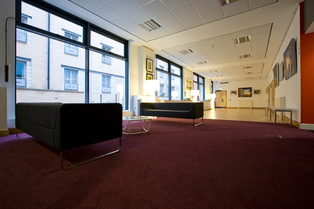 A spacious office featuring a large window and a comfortable couch for relaxation or informal meetings.