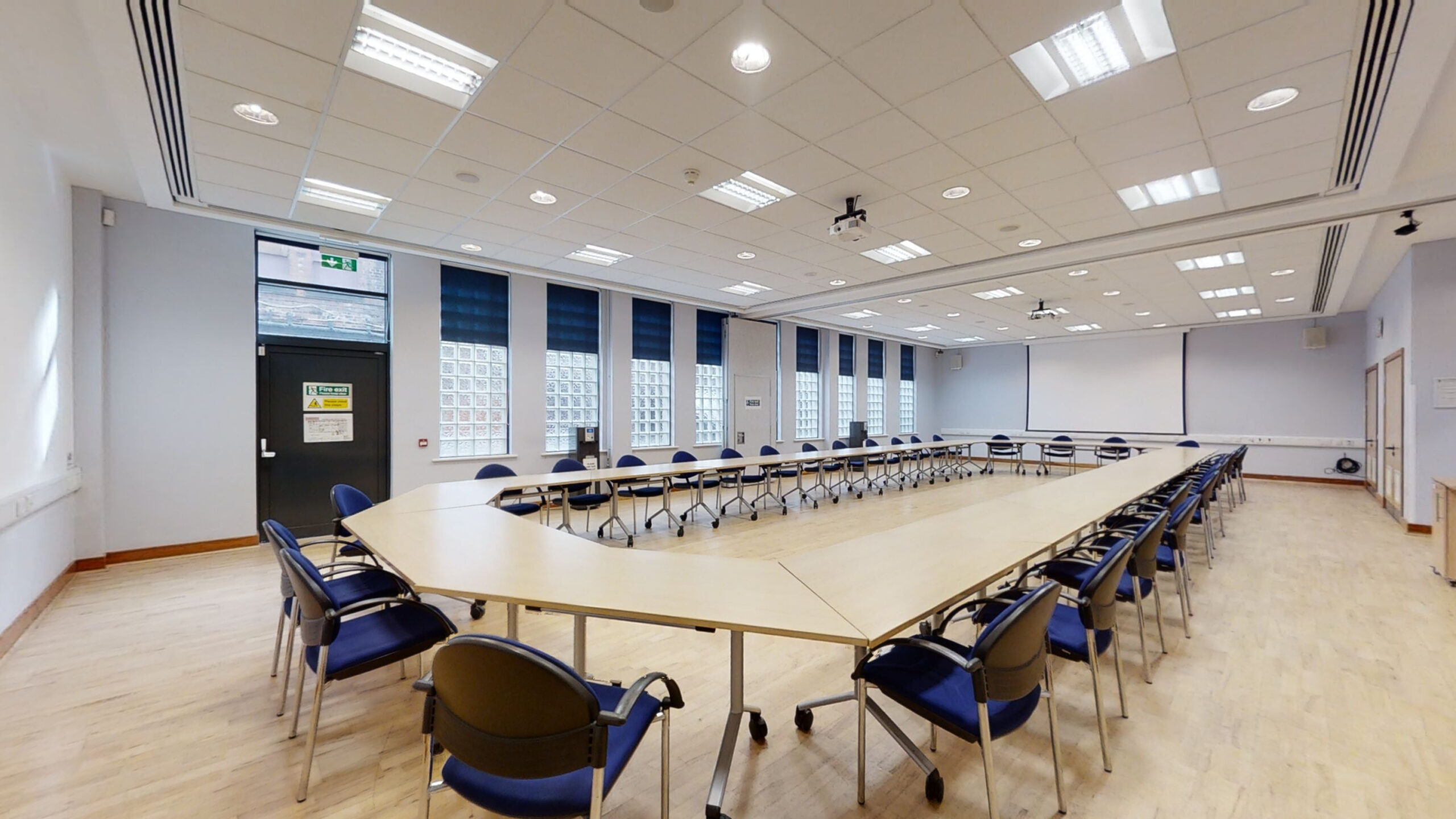A spacious conference room featuring multiple tables and chairs arranged for a meeting or presentation.