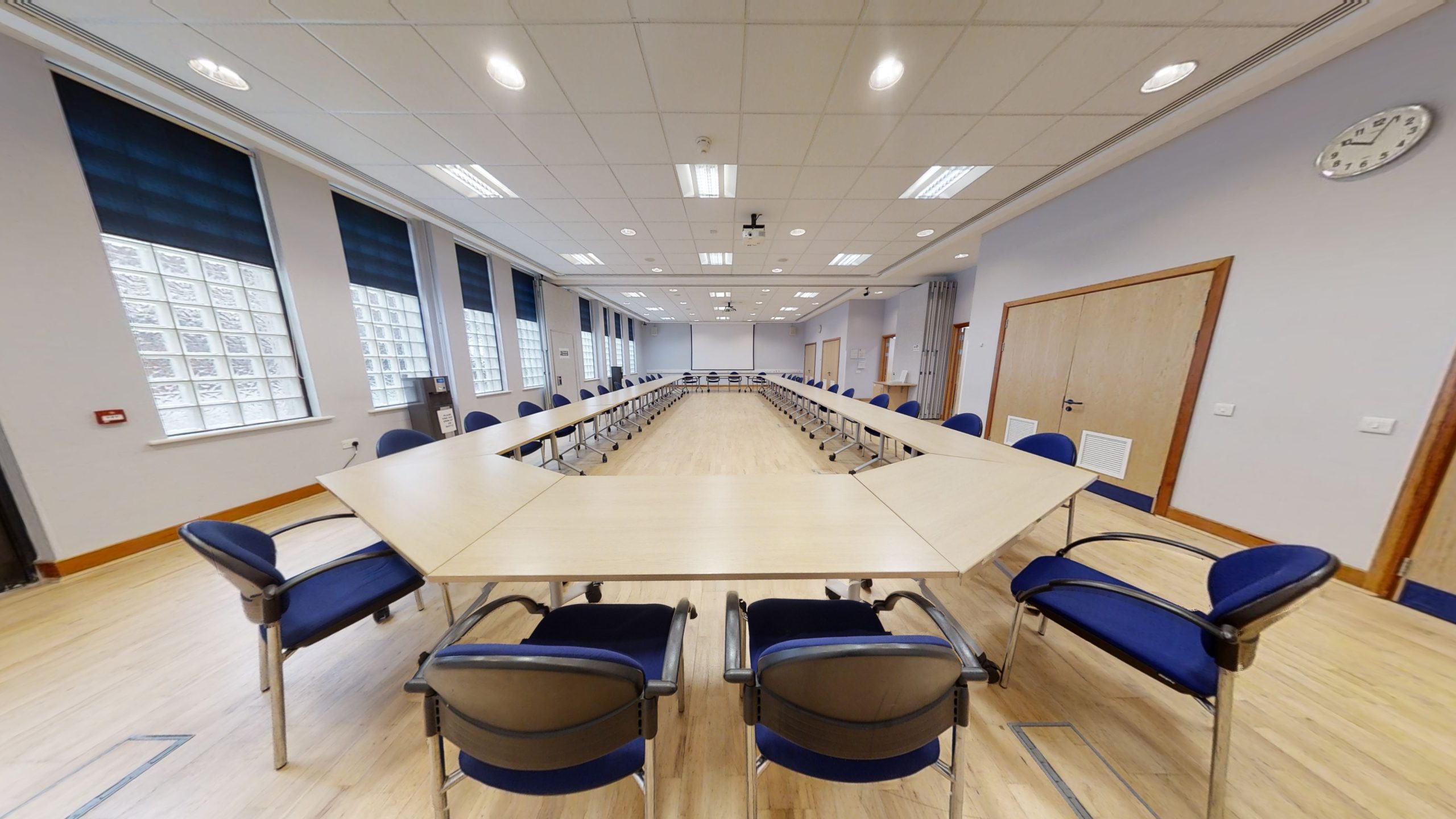 A spacious conference room featuring rows of blue chairs arranged for a meeting.