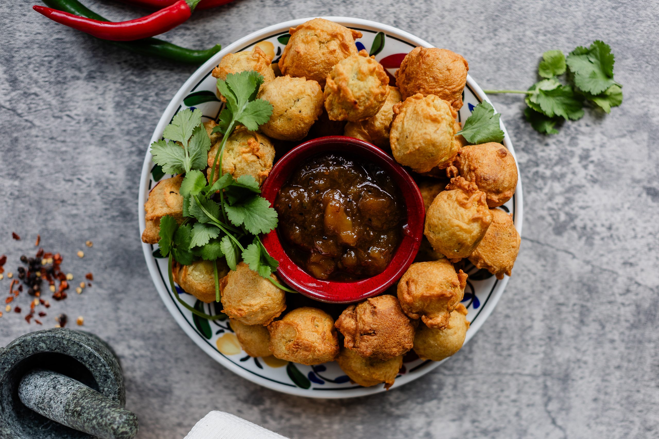 Fried chicken served on a plate, accompanied by a savory sauce and garnished with fresh chili peppers.